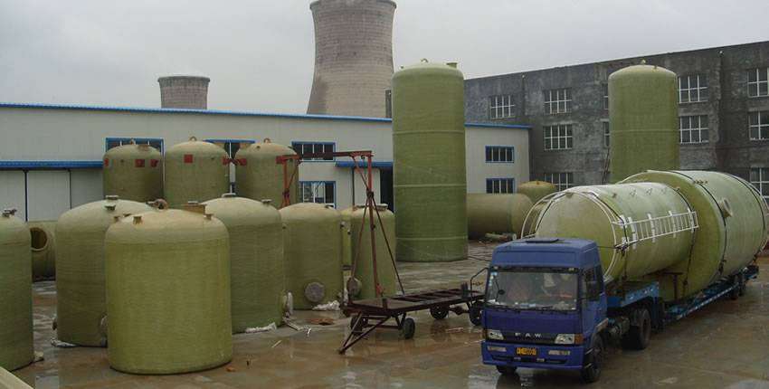 Two vertical FRP tanks are packed on a blue truck, while others are placed in the yard.
